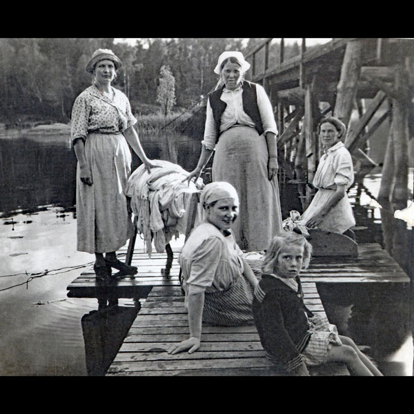 Kvinnor och barn tvättar kläder i Magelungen vid Farstanäsets första militärbron ca 1925. Foto: Okänd