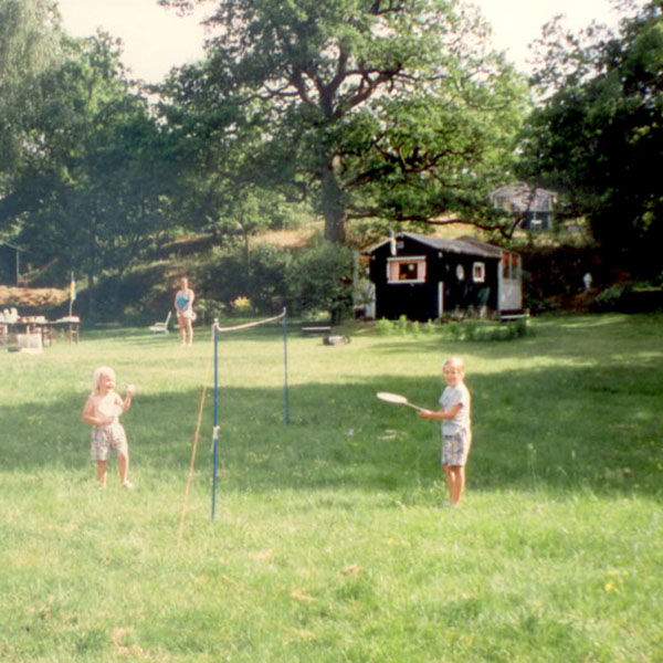 Barn som spelar badminton vid övre ängen. Stuga 15 i bakgrunden. 1990