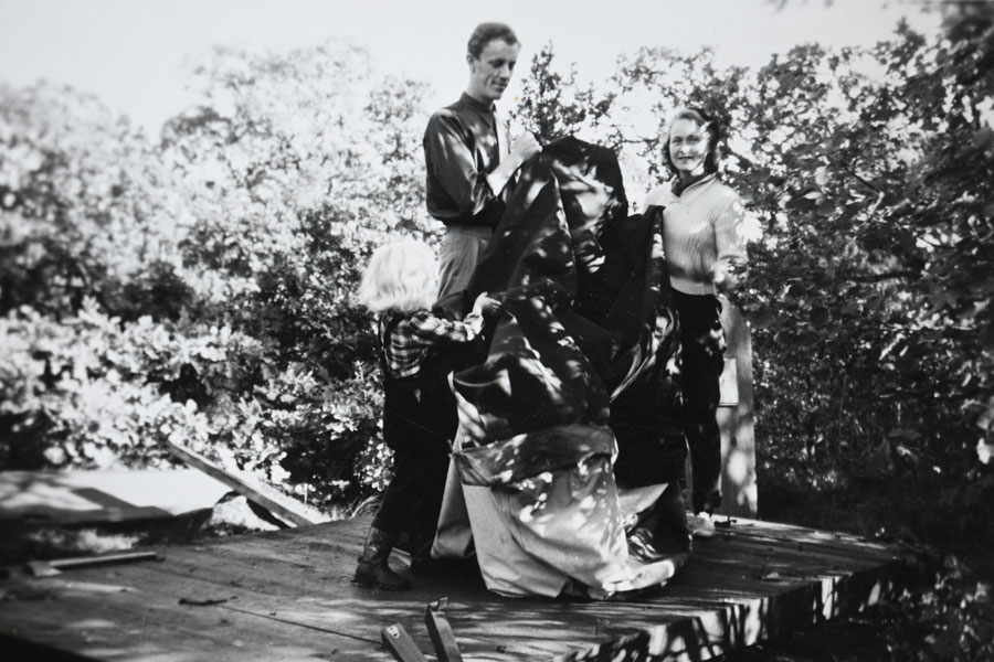 Sommar 1953: Sonia hjälper pappa och moster att sätta upp tältet på den hyrda tältbottnen medan pappa håller på att bygga stugan.